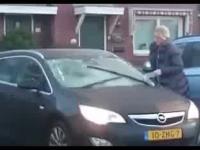 Kobieta usuwa lód z szyby swojego samochodu